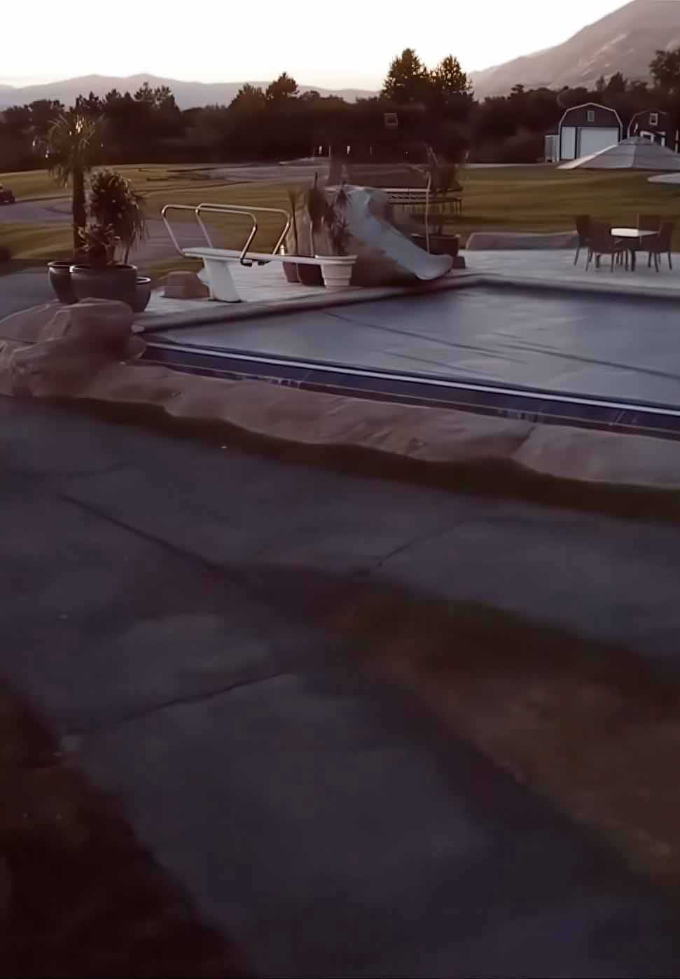 inground swimming pool at sunset with safety cover